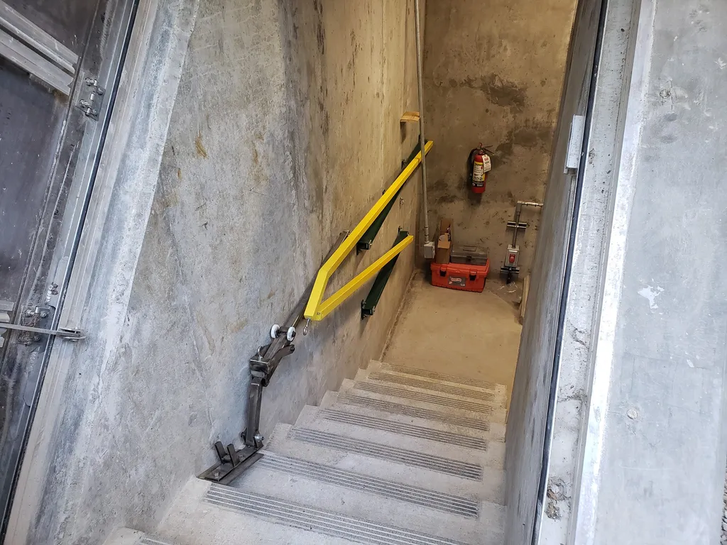 Collapsible pit handrails deployed at full 42-inch height along a locomotive service pit edge